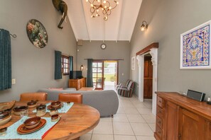 A dining area with a round table set for four, a sofa, and a television. - NEW ! Casa Kudawecha (Casa and Casita) (Noord)