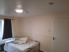 Cozy single-bed room with a floral-patterned bedspread and a plain white blanket.