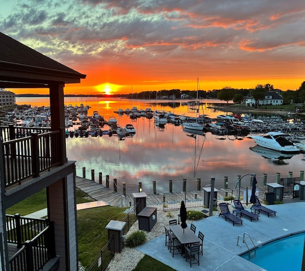 A marina with boats docked, a pool area with lounge chairs, and a sunset view. - Lakefront Condo (Cornelius)