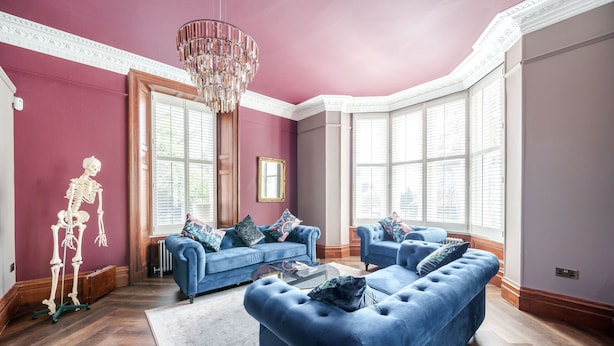 Un salon avec deux canapés bleus, un lustre et une décoration sur le thème du squelette.