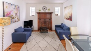 A living room with two blue sofas, a TV, a fireplace, and artwork on the walls. - British Character in Golders Green. ground floor. 20min to oxford st. (London)