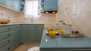 Una cocina con armarios azul claro, encimera blanca y salpicadero de azulejos.