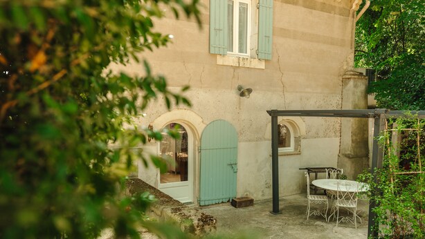 A courtyard with a white table and chairs, a blue door, and a stone wall.