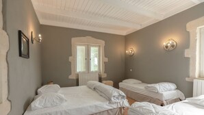 A room with two beds, a window, and wall sconces.