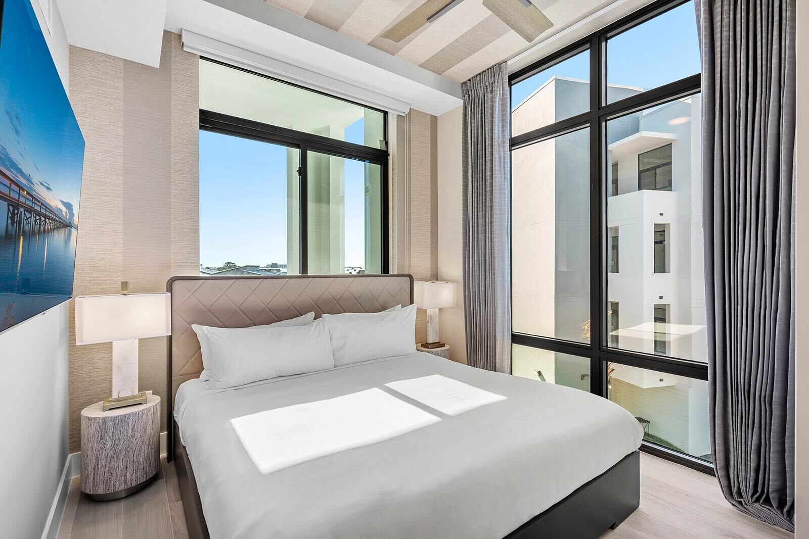 A modern hotel room with a large bed, a view of the city, and a large window.