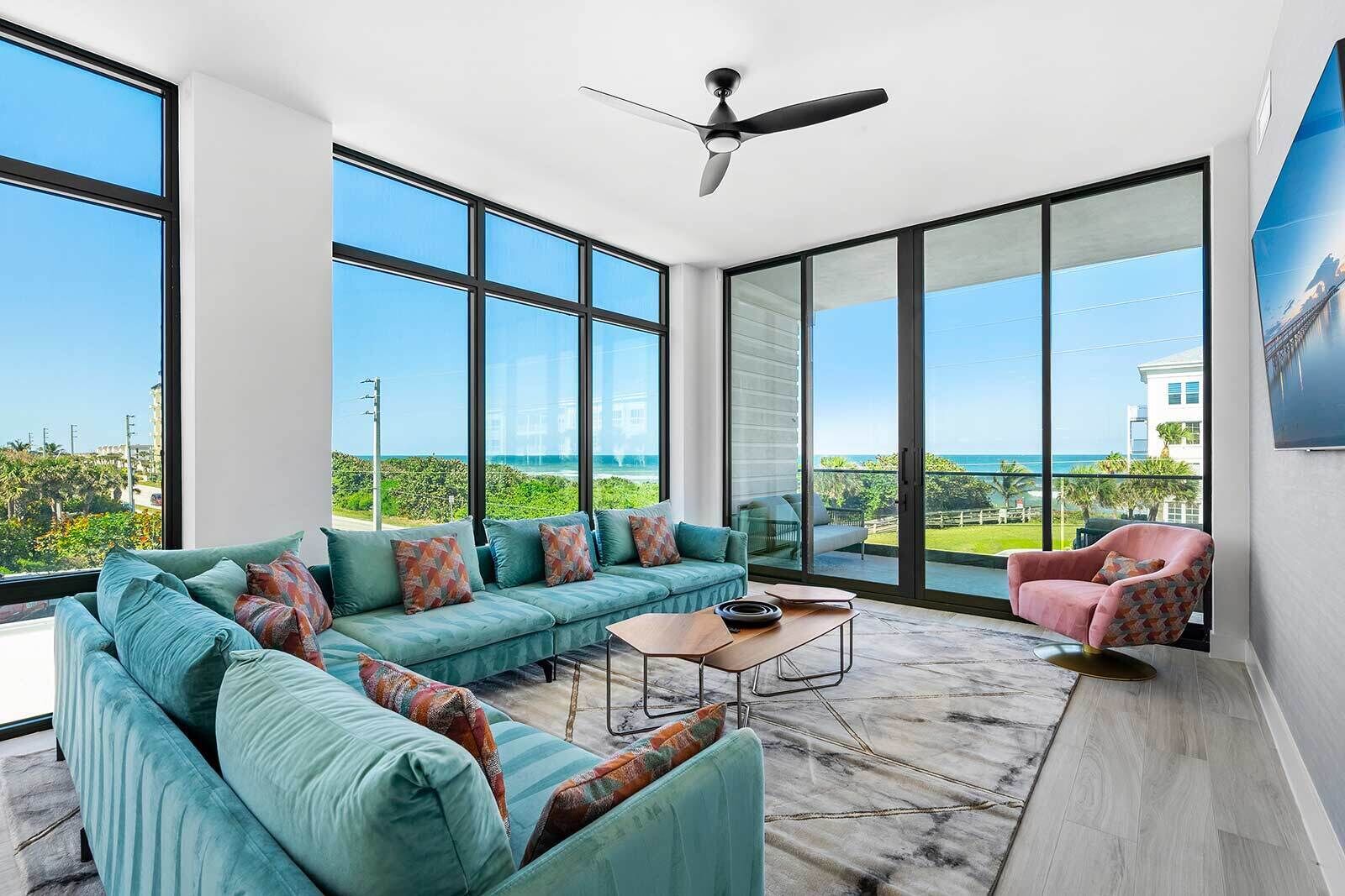 A modern living room with a large sofa, a coffee table, and a pink armchair.