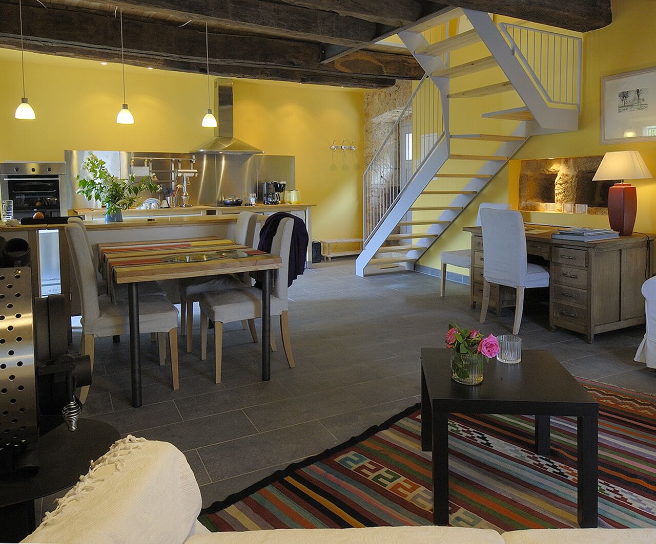 Un vaste espace de vie comprenant une table à manger, des chaises, un canapé et un escalier menant à l’étage supérieur.