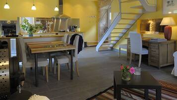 Un vaste espace de vie comprenant une table à manger, des chaises, un canapé et un escalier menant à l’étage supérieur.