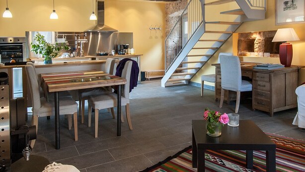 A modern kitchen with a dining area, a staircase, and a living space with a desk and chair. - Gite de la Cascade, Pour 4 Personnes, Animaux Acceptés, Entre Rodez et Conques (Salles la source)