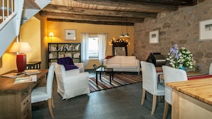 A cozy living room with a staircase, a fireplace, a bookshelf, and a dining area. - Gite de la Cascade, Pour 4 Personnes, Animaux Acceptés, Entre Rodez et Conques (Salles la source)