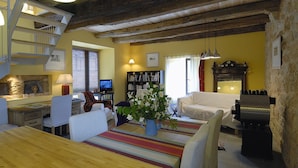 A cozy living room with a wooden staircase, a dining area, and a bookshelf. - Gite de la Cascade, Pour 4 Personnes, Animaux Acceptés, Entre Rodez et Conques (Salles la source)