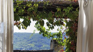 A wooden deck with a round table and metal chairs, surrounded by a pergola with climbing plants. - Gite de la Cascade, Pour 4 Personnes, Animaux Acceptés, Entre Rodez et Conques (Salles la source)