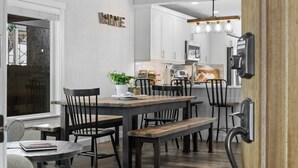 Una cocina moderna con armarios blancos, una mesa de comedor de madera y sillas negras.