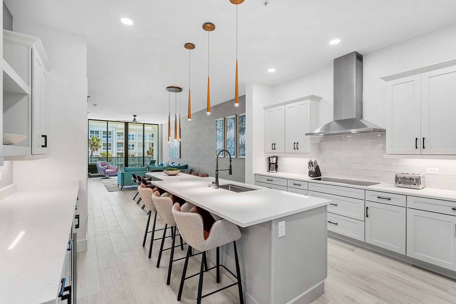 A modern kitchen with a central island, bar stools, and pendant lighting.