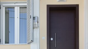 A dark brown door with a handle and a keyhole, leading to a set of stone steps. - Garitsa Gem Suite (Corfu)