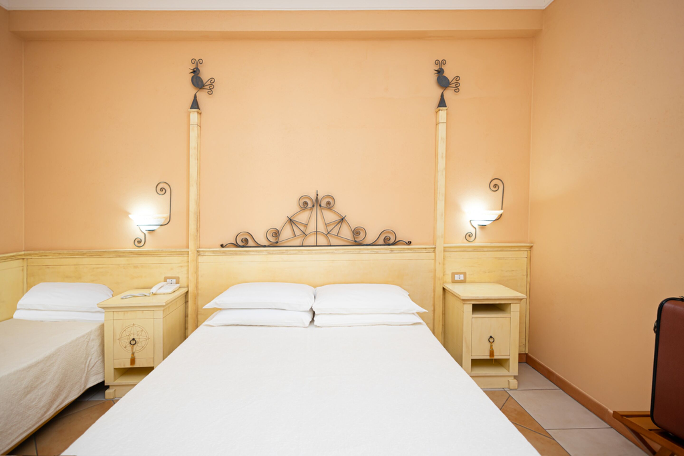 Una habitación de hotel con una cama grande, dos mesitas de noche y lámparas de pared.