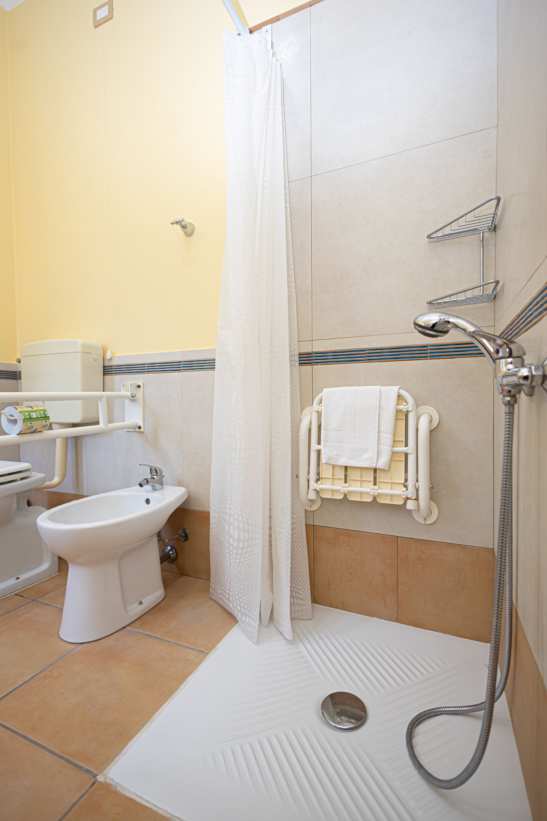 Ein Badezimmer mit Dusche, Toilette, Bidet und Handtuchhalter.