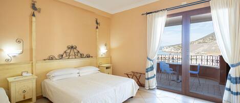 Habitación de hotel con cama, mesitas de noche, cortinas y vistas al exterior.