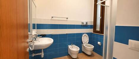 Un baño con lavamanos, dos inodoros, un bidé y zona de ducha.