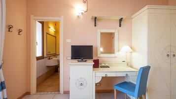 Una camera d'albergo con scrivania, sedia, televisore e armadio.