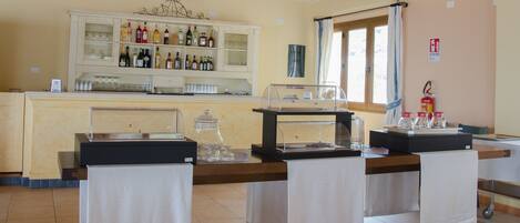 Un espace bar avec un présentoir pour les boissons alcoolisées, un coin café et un extincteur.