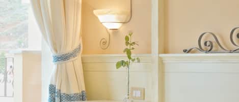 A neatly made bed with a tray of breakfast items, a bedside table with a lamp, and a window with curtains.