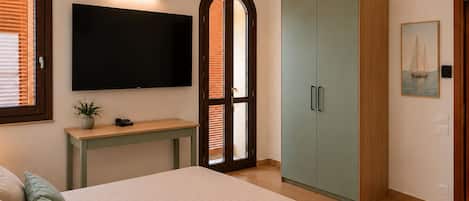 A bedroom with a bed, a TV, a desk, and a wardrobe.