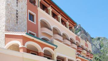 Un hôtel à plusieurs étages, doté d’une façade en pierre, de nombreux balcons et surplombant un paysage montagneux.