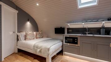 A bedroom with a bed, a bedside table, and a built-in TV.