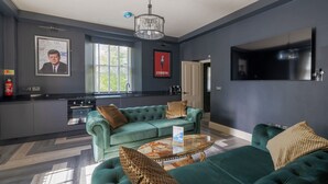 A modern living room with a green sofa, a coffee table, and a TV mounted on the wall.