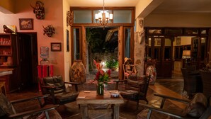 A cozy lounge area with leather chairs, a central table, and a large vase of flowers. - Casa  Don Juan (Compostela)