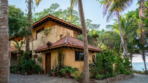 A two-story building with a tiled roof, surrounded by lush greenery and a cobblestone path. - Casa  Don Juan (Compostela)