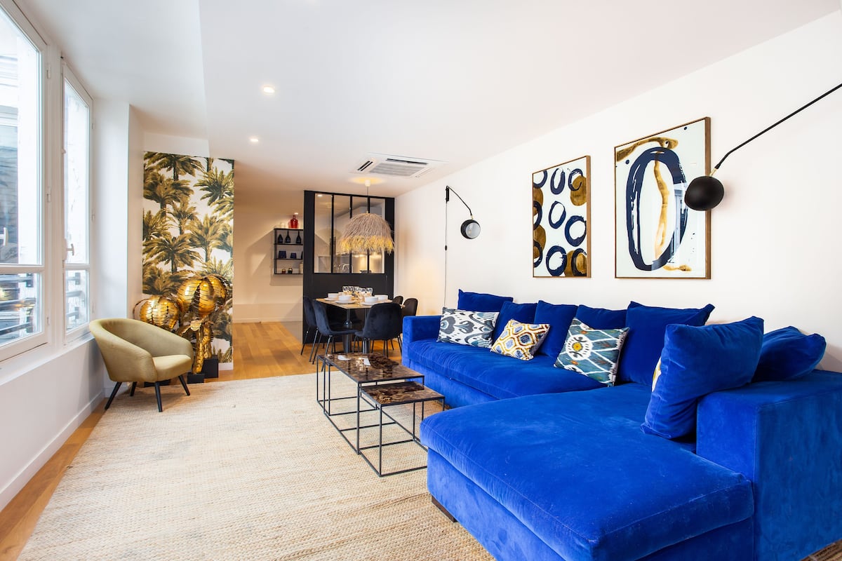 Uma sala moderna com um sofá azul, um espaço de jantar e uma janela grande.