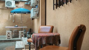 A small outdoor seating area with a table and chairs, a patterned tablecloth, and an air conditioning unit in the background. - Armena Hostel (Yerevan)