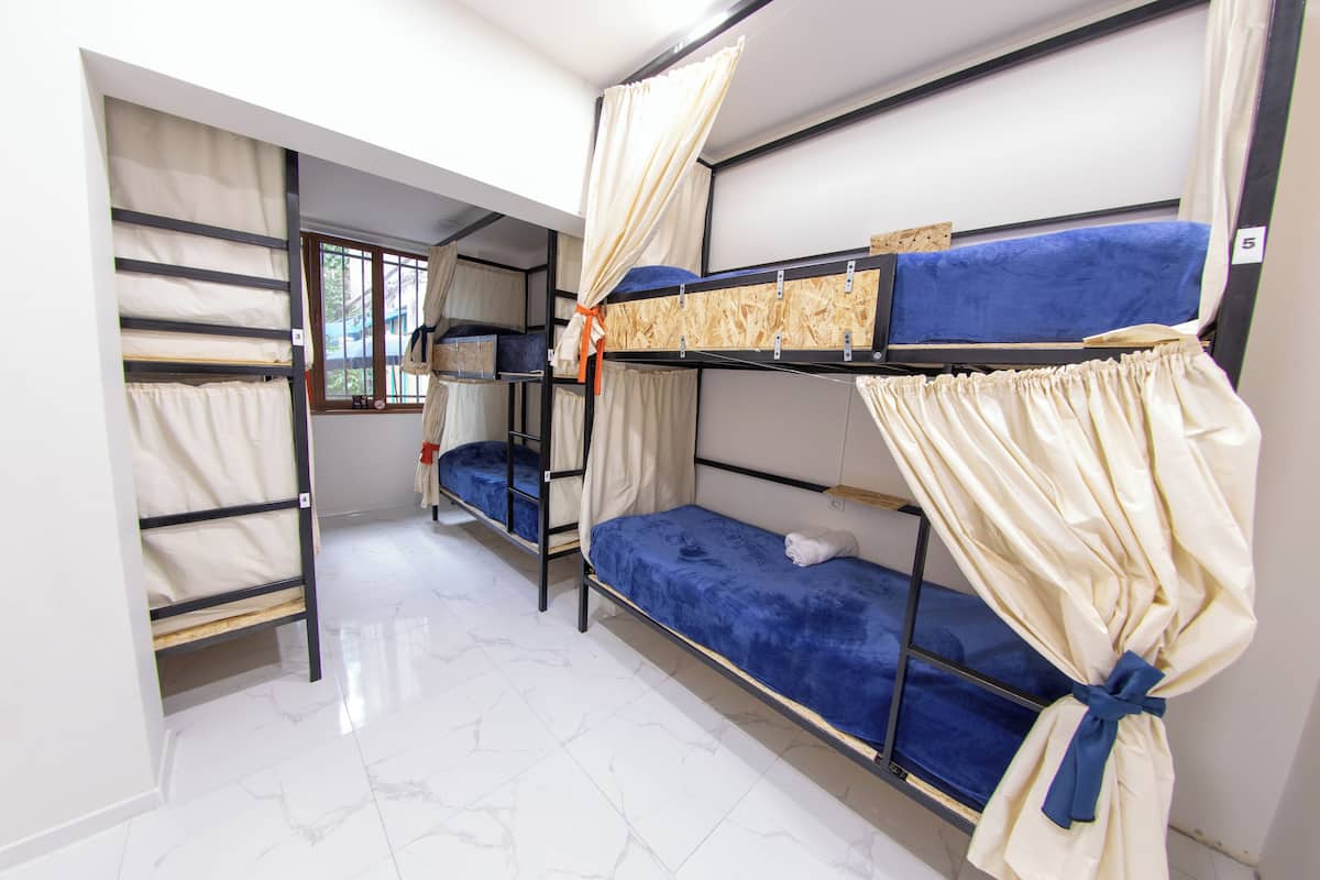A dormitory room with bunk beds, a window, and a tiled floor.