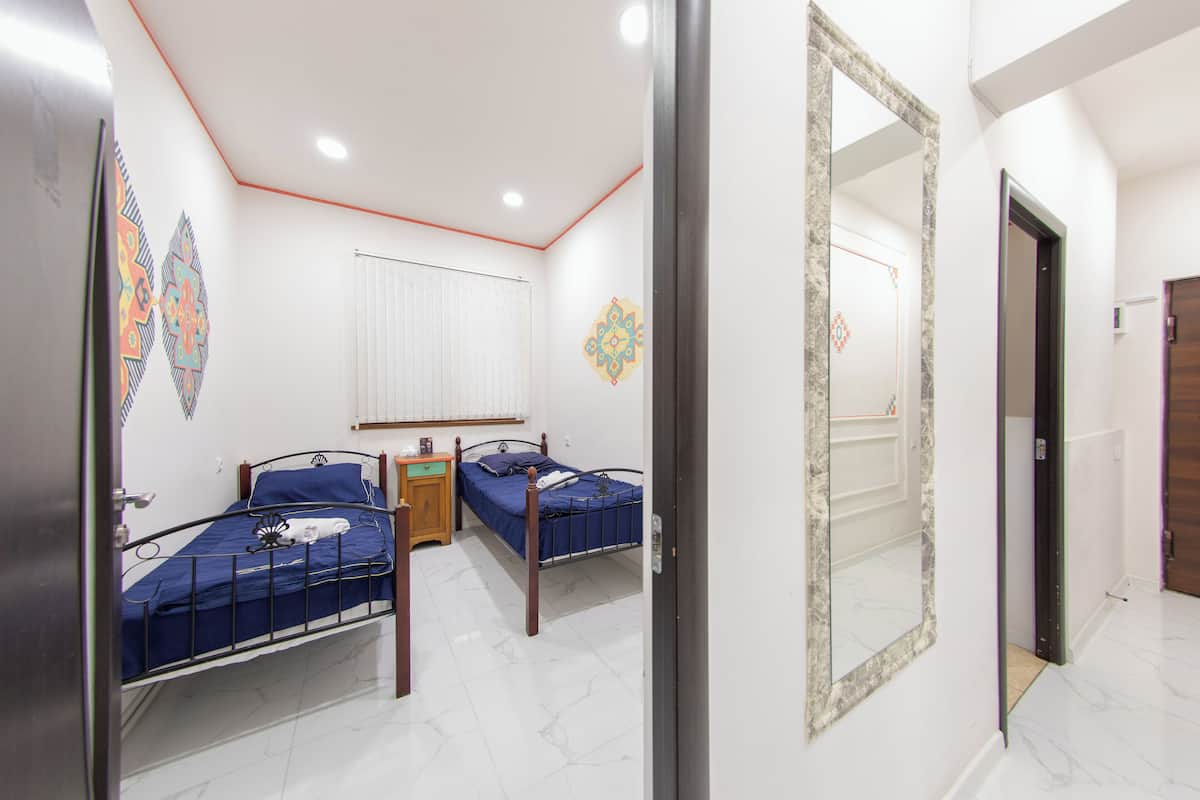 A bedroom with two single beds, a wooden nightstand, a mirror, and decorative wall art.