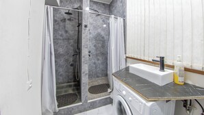 A modern bathroom with a shower, a washing machine, and a sink with a bottle of soap. - Armena Hostel (Yerevan)