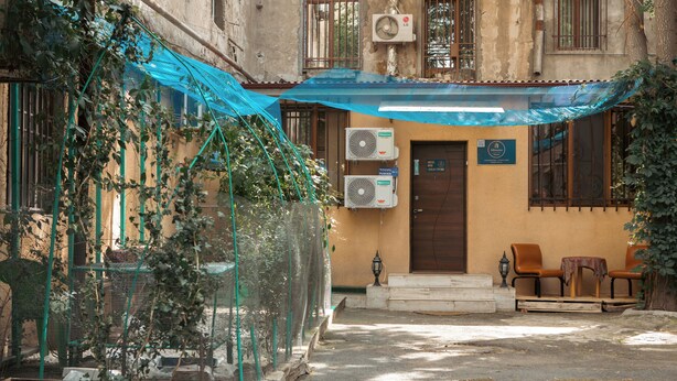 A courtyard with a covered seating area, a small table, and a potted plant. - Armena Hostel (Yerevan)