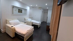 Quarto de hotel com duas camas, uma TV de tela plana na parede e uma pequena mesa de cabeceira.