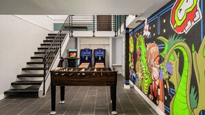 Un espace intérieur moderne doté d’un baby-foot, de jeux d’arcade et d’une fresque murale aux couleurs vives.