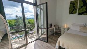 Un dormitorio con un amplio ventanal corredera que da a un balcón con mobiliario exterior.