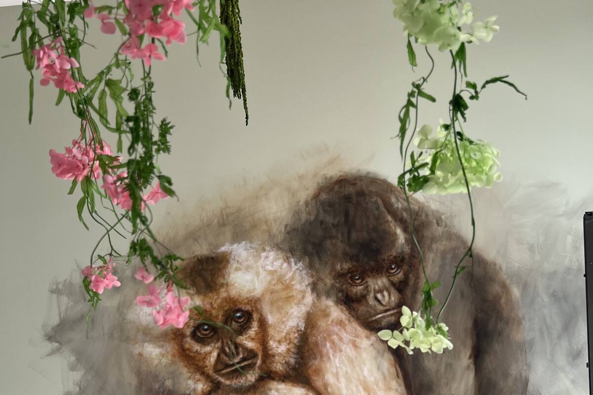 A painting of two gorillas with pink flowers hanging above them.