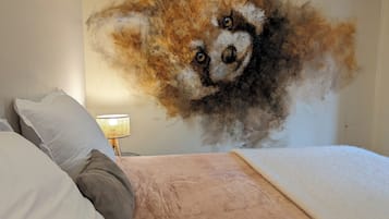 Un dormitorio con un cuadro grande de un zorro en la pared, una cama con almohadas y una lámpara de noche.