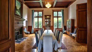 Un comedor formal con una larga mesa, sillas, una chimenea, estanterías y ventanas grandes.