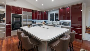 Una cucina moderna con isola centrale, sgabelli da bar ed elettrodomestici integrati.
