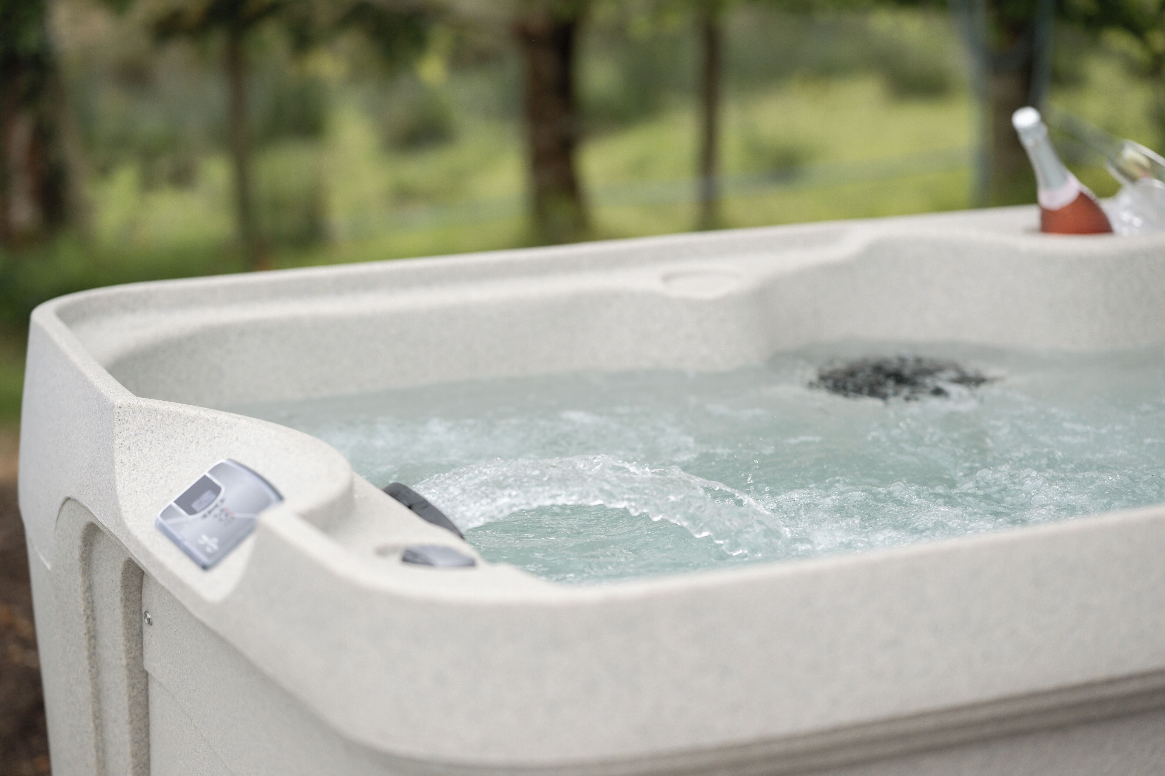 A hot tub with a control panel and a bottle of champagne.