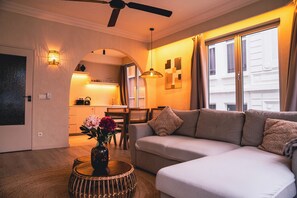 A modern living room with a sofa, a coffee table with a vase, and a kitchen in the background. - SLEEP INN ANTWERP - Japandi Lofts (Antwerp)