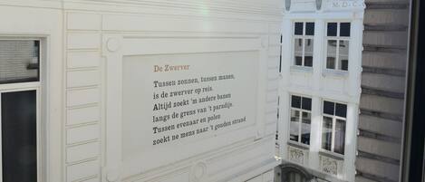 A white building facade with a plaque containing text in Dutch.