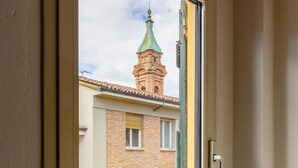 A window with a view of a building with a green roof and a tower. - Comfort Urbano a Porta Maggiore by Wonderful Italy (Bologna)
