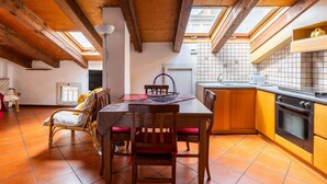 A cozy kitchen with wooden beams, a dining area with chairs and a table, and a view through skylights. - Comfort Urbano a Porta Maggiore by Wonderful Italy (Bologna)